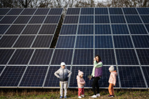 Mother with three kids on the background of solar panels